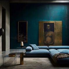 a living room with blue couches and paintings on the wall in front of it