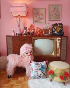 a pink room with an old fashioned television and stuffed animals