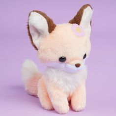 a small stuffed fox sitting on top of a purple background