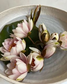 some pink flowers are in a white bowl