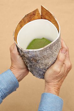 a person holding up a paper cup with something green in it and some sticks sticking out of it