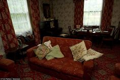 a living room filled with red couches next to two tables and chairs in front of windows