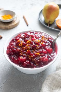 a white bowl filled with cranberry sauce next to an apple