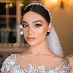 a woman in a wedding dress with a veil and tiara on her head, looking at the camera