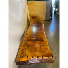 a wooden bench sitting on top of a cement floor next to a white wall in a building