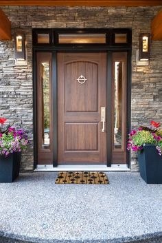 two planters with flowers are on the front steps of a house, next to a door