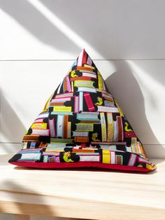 a colorful triangle shaped pillow sitting on top of a wooden table next to a white wall