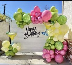 a happy birthday sign made out of balloons and limes on the side of a building