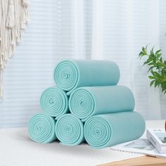 a stack of rolled up blue towels next to a potted plant on a table