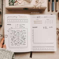 an open planner book sitting on top of a wooden table next to other office supplies