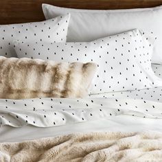 a bed with white sheets and black dots on it