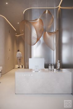 a man standing in front of a white counter with lights hanging from it's ceiling