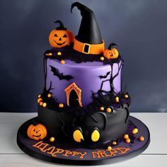 a halloween cake decorated with black and purple icing, pumpkins and bats on top