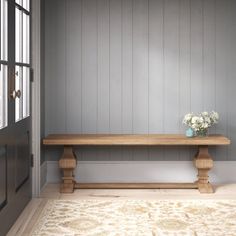 a wooden bench sitting in the middle of a room next to a door and window