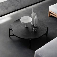 two white vases sitting on top of a black coffee table next to couches