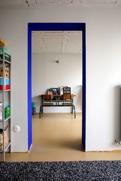 an empty room with a blue door and bookshelf on the wall, in front of a television