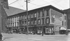 an old black and white photo of people walking down the street in front of buildings