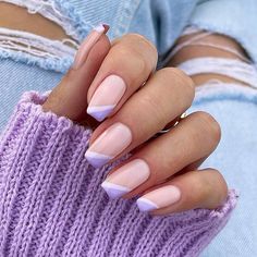 a woman's hand with pink and white nail polish on her nails, holding a purple