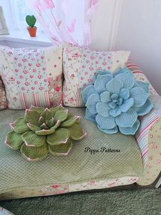 a couch covered in pillows and flowers next to a potted plant