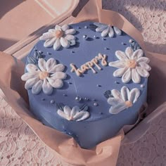 a blue cake decorated with white flowers and the words happy written on it in frosting