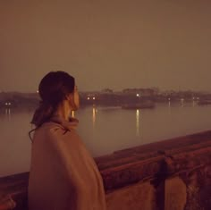 a woman is looking out over the water at night