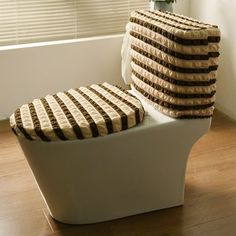 a white toilet sitting on top of a hard wood floor next to a window with blinds