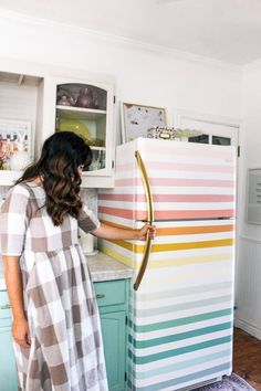 a woman standing in front of a refrigerator with colorful stripes on the door and bottom