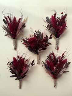 four bouquets of flowers are arranged on a white table top with dried stems and leaves