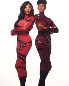 two black women in red bodysuits standing next to each other with their arms crossed