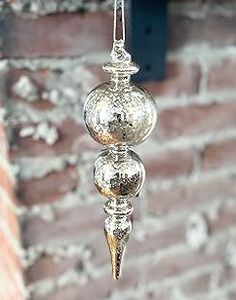 three glass balls hanging from a chain in front of a brick wall with a window