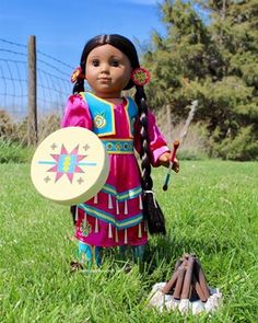 an american girl doll holding a frisbee in her hand and standing on the grass