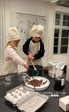 two children in chef's hats are making chocolate cake with utensils on the table