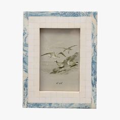 two seagulls flying over the water in a blue and white tile photo frame