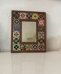 a mirror sitting on top of a white counter next to a vase and potted plant