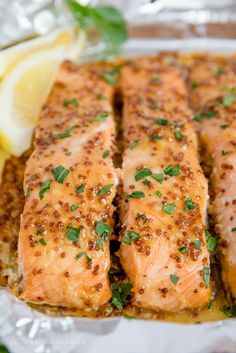 cooked salmon fillets on foil with lemon wedges and parsley sprigs