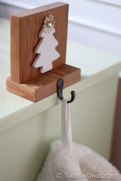 a wooden stand with a white christmas tree on it and an umbrella hook attached to it