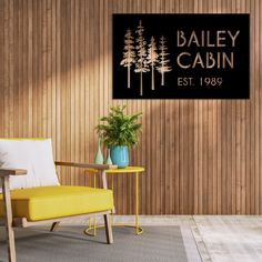 a yellow chair sitting in front of a wooden wall with a sign that says bailey cabin