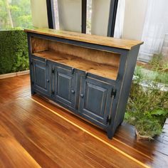 a large wooden cabinet sitting on top of a hard wood floor next to a window