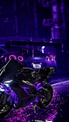 a motorcycle parked on the side of the road in front of a car at night