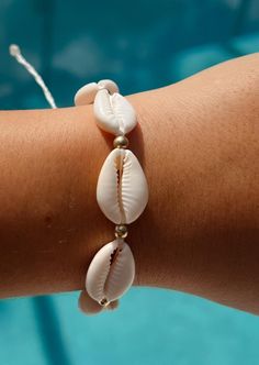 Shimmer in the sun and show off your surf wardrobe with our Amelia Bracelet! Featuring shining gold accents and classic cowrie shells, this set is sure to add a delicate touch to your outfit.  Cream Lacquered Cowrie Shells Gold waterproof beads Wax Cord approx 6" with adjustable 3.5" knot - adjustable and waterproof! Matching necklace and anklet!  Mix and match with your favorite HALT pieces or wear alone for boho beach vibes. The perfect gift for her! Our jewelry is handmade in the Sunshine State with local materials and shipped with an effort to use environmentally friendly packaging, making it the perfect choice for those who shop with a green mindset. Earthy Beige Beach Jewelry, Beachy Gold Shell Bracelets, Beach Jewelry Aesthetic, Earthy Hand-wrapped Bracelets For The Beach, Beachy Shell-shaped Bracelets For Gift, Adjustable Shell-shaped Beachy Bracelets, Outfit Cream, Vacation Accessories, Coastal Aesthetic