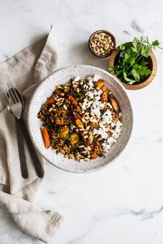 a bowl filled with rice, carrots and other food on top of a table