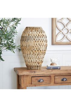 a vase sitting on top of a wooden table next to a potted plant and books