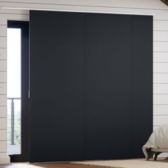 a black sliding door in a room with white walls and wood flooring on the side