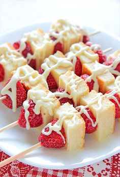 strawberry shortbreads with white icing on a red and white tableclothed cloth