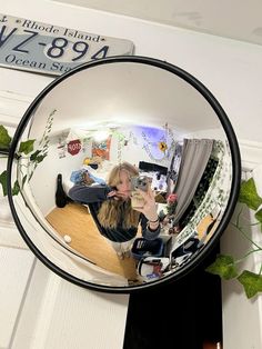 a woman taking a selfie in a mirror on the door way to her apartment