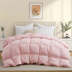 a bed with pink comforter and pillows in a room