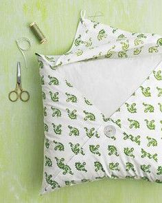 a pillow and scissors are laying next to each other on a table with green wallpaper