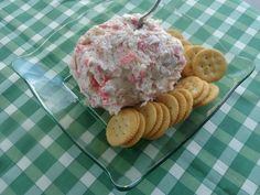 a bowl of food with crackers on the side sitting on a green and white checkered tablecloth