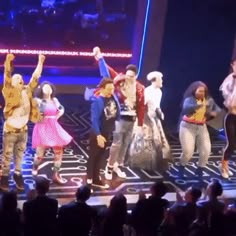 a group of people standing on top of a stage with their arms in the air