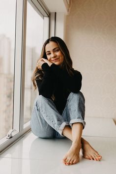 a woman sitting on the floor next to a window